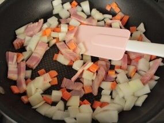 ②フライパンにオリーブオイルを入れてベーコン・玉ねぎ・人参・塩コショウを弱火で炒める