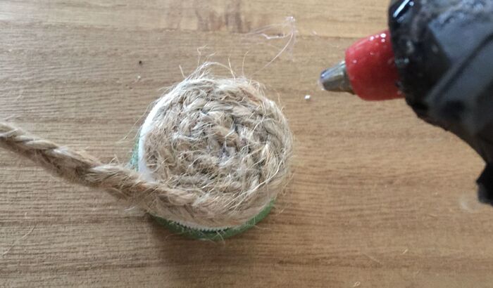 三つ編みにした麻ひもを、グルーガンでキャップに接着します。