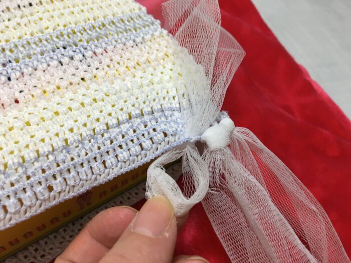 ネットを三つ折りにして、網目にくくっていく。