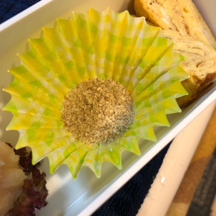 おかずカップにすりごまを敷く