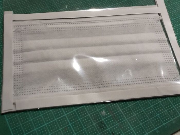 マスクを袋に入れ、サイズに合わせて両面テープを貼る。裏側も。