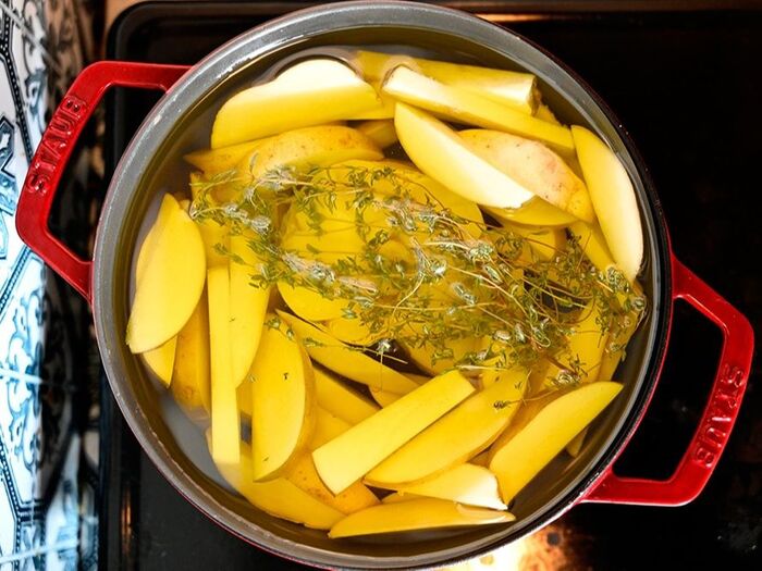 作り方1:じゃがいもとにんにくを鍋に詰め、お好みのハーブをのせた上からオイルをひたひたに注いでから中火にかける。