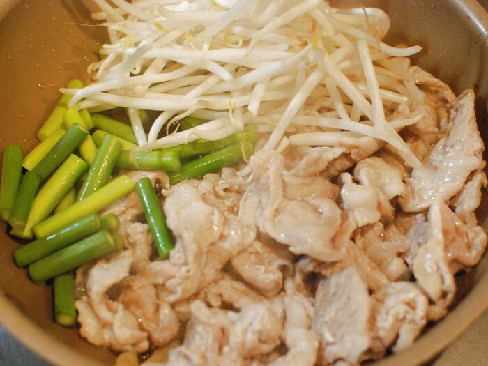 豚こまの色が変わったら、にんにくの芽ともやしを入れます