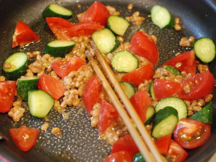 納豆に火が通ってきたら、トマトときゅうりを入れます