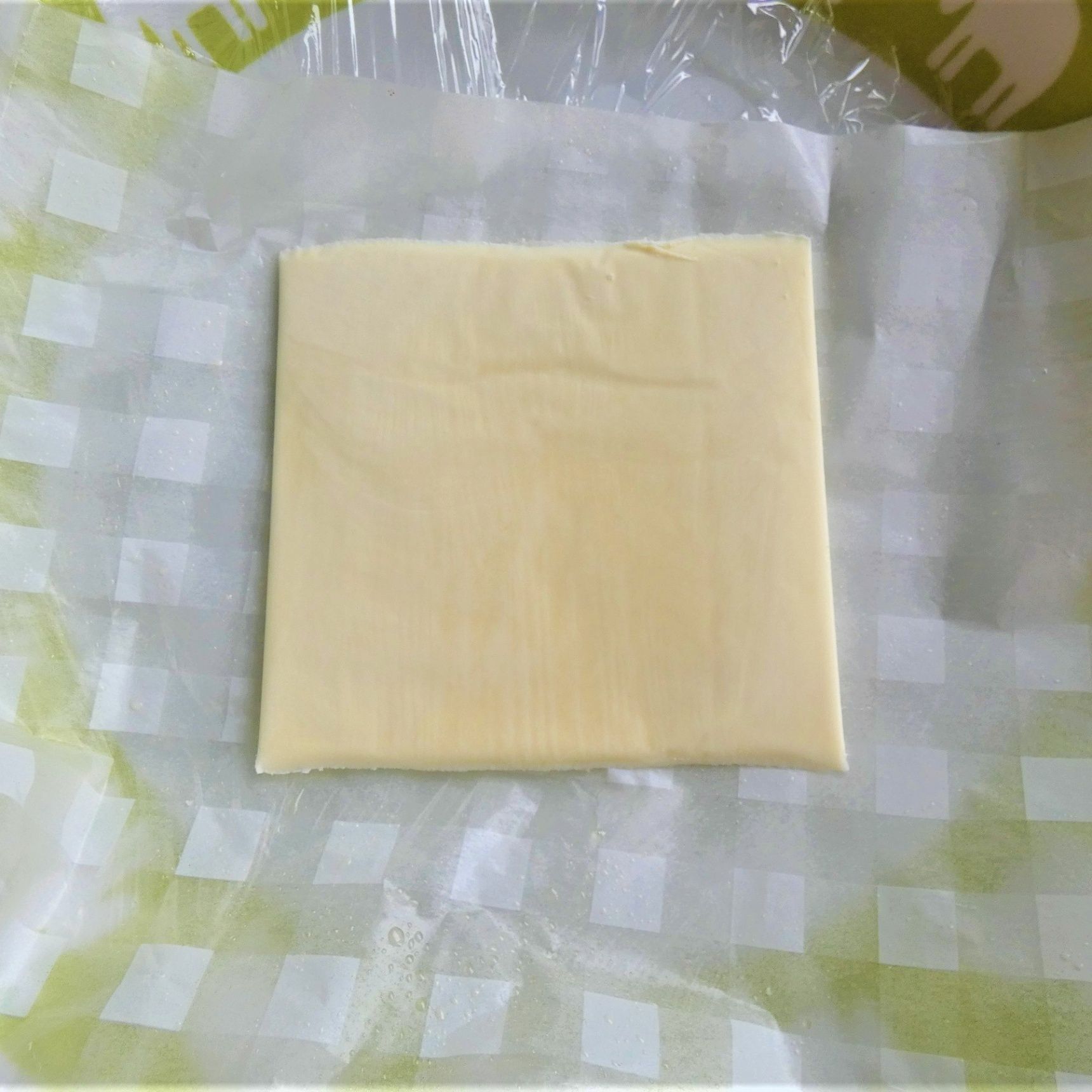 電子レンジ可のお皿にラップ・クッキングシート・チーズを乗せる。
