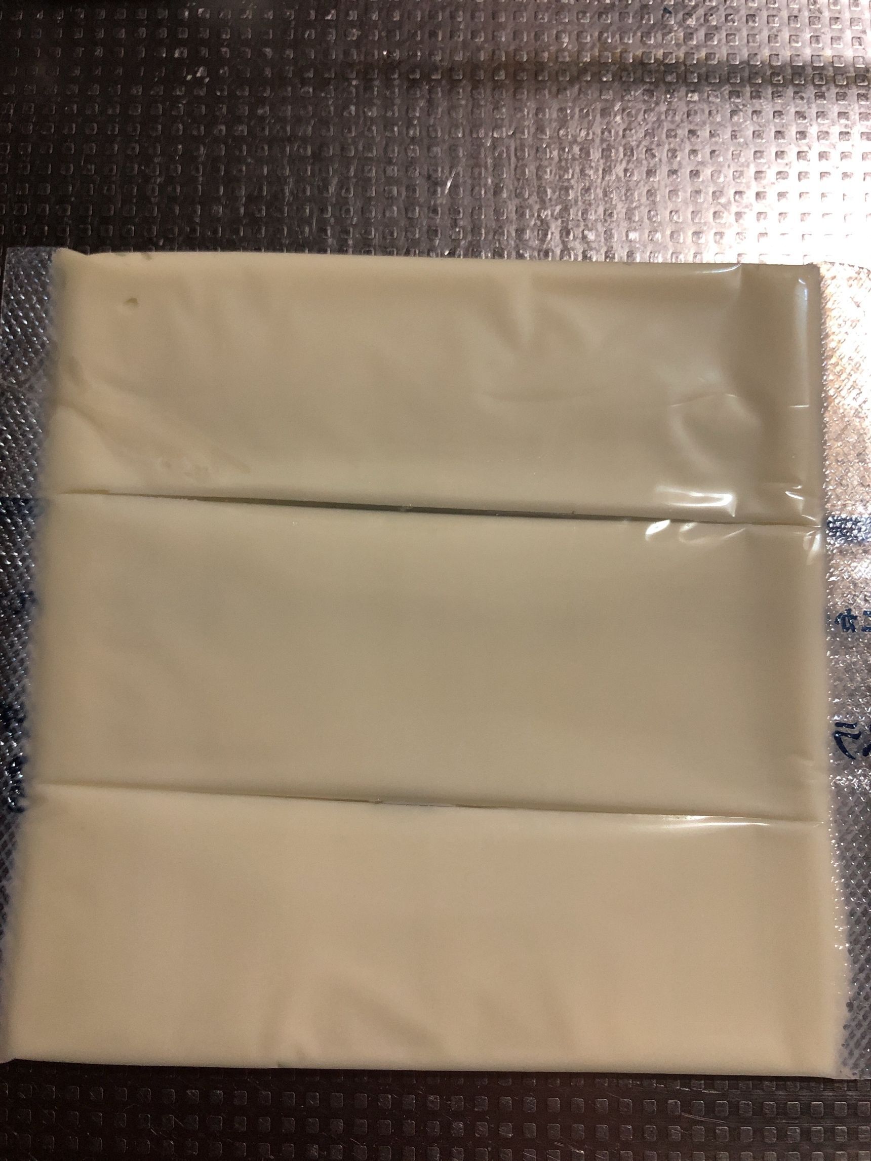 スライスチーズをフィルムの上から包丁で切ります