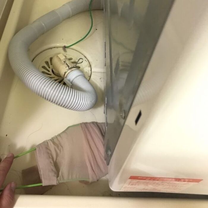 2)-2 洗濯機の下にハンガーを差し込み、ホコリをとる