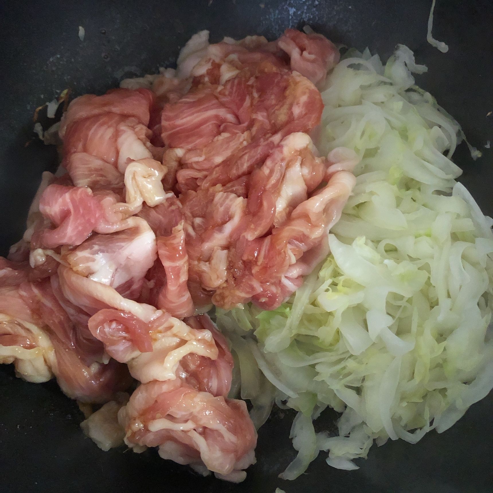 別のフライパンでキャベツと玉ねぎを炒め、しんなりしてきたら豚肉を加えて炒めます