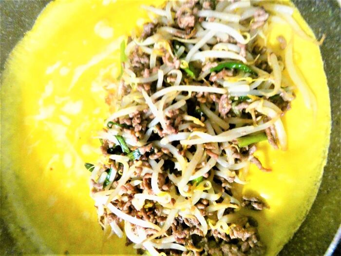 肉・野菜を炒めて塩コショウで味付け。卵を焼いて炒めた野菜を包みます。