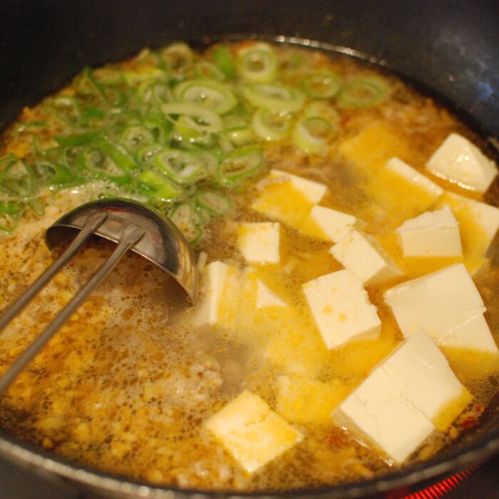 ねぎ小口切りと、食べやすい大きさに切った豆腐を加えます