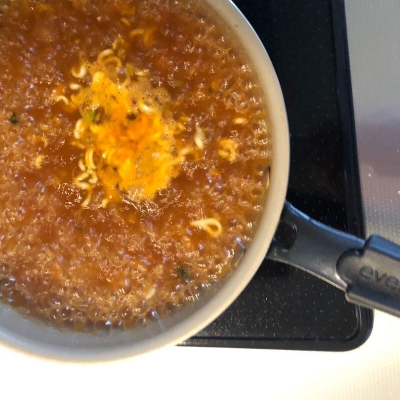 ズボラーナ…1（1）…1.で麺を取り出した茹で汁にいつもの赤い粉と赤いかやくを投入し再加熱します。