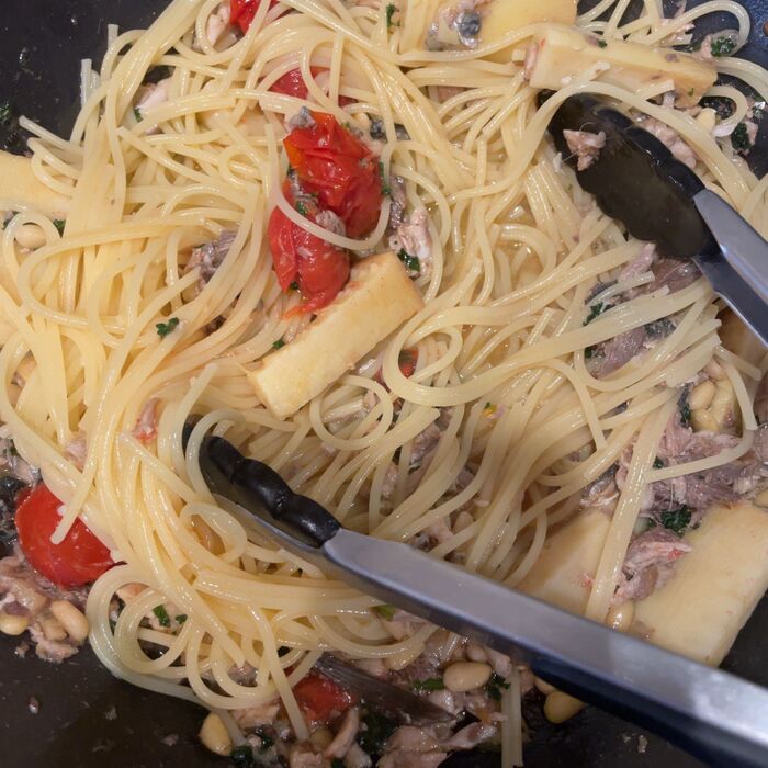 茹でたパスタをパスタソースに絡めます