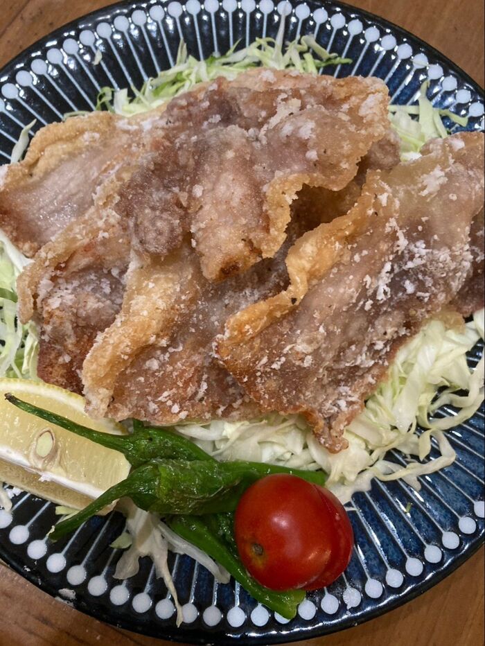 千切りキャベツたくさんの上に唐揚げを乗せてレモン、トマト、しし唐を飾ります♪