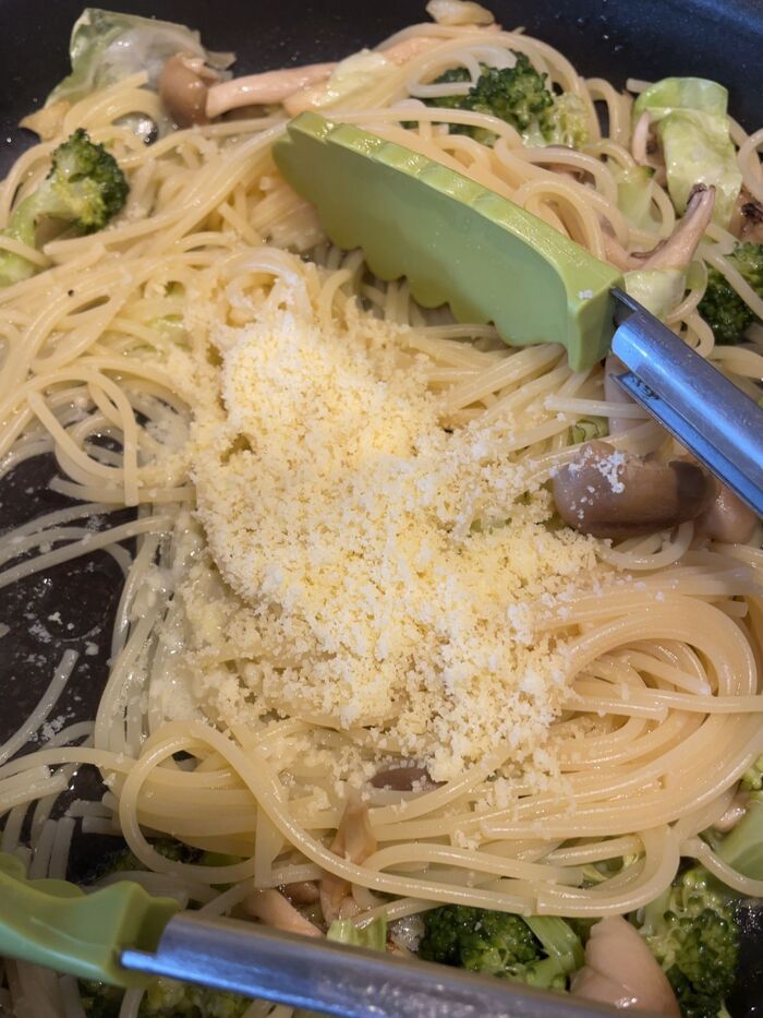 パスタをフライパンに加え、パルメザンチーズを加えます