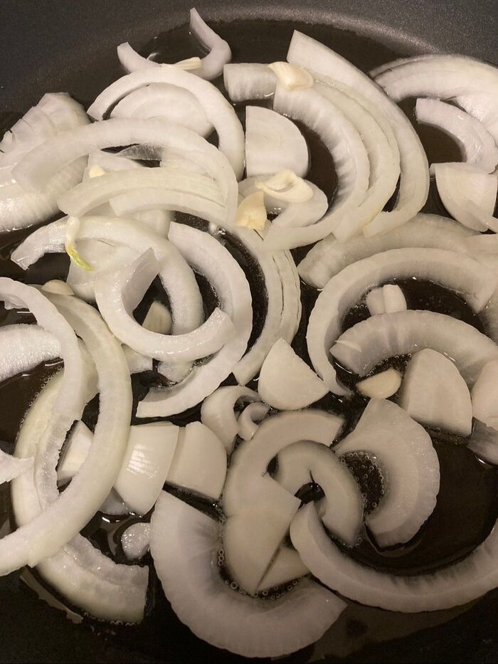 フライパンにニンニクのスライスと玉葱を敷き詰めます