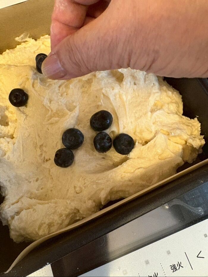 ケーキ型にシートを敷いてからタネの半分量を入れてブルーベリーを散らします。