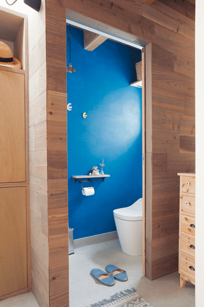 古材風の板張り壁とブルーのペイントがコントラストのトイレ