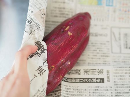 さつまいもを新聞紙で包む