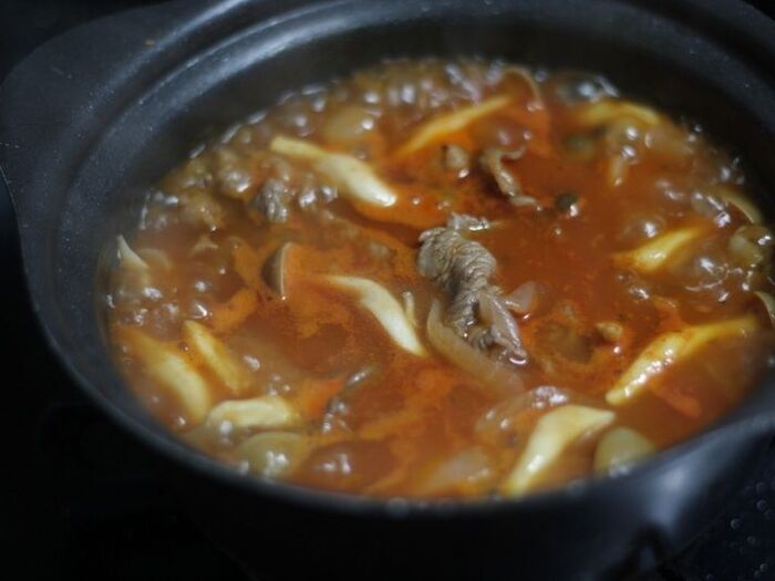 材料を炒めてスープを加えて煮込んで味を調える。