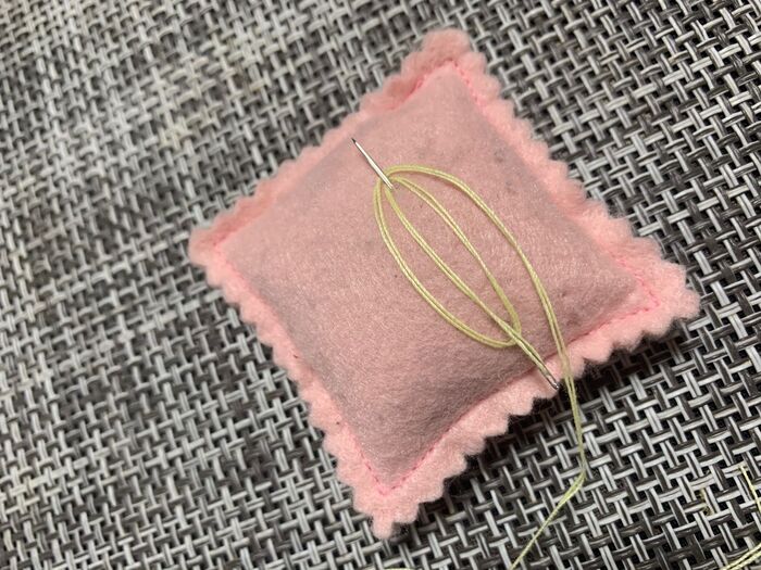 針についている糸を、針先に引っ掛けて「の」字を描くように、ぐるぐる巻く。