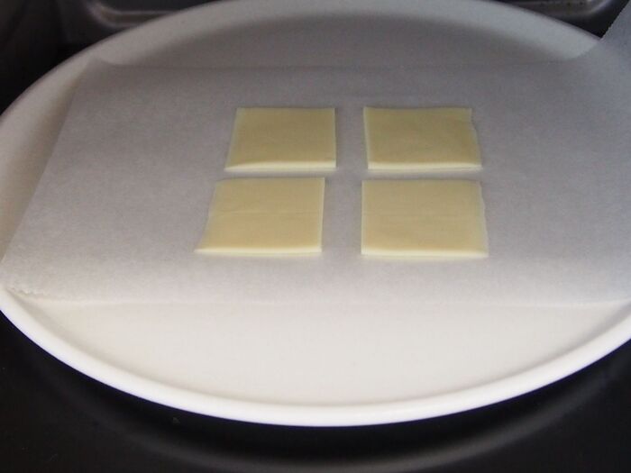 ②クッキングペーパーを敷いた上に4つに切ったチーズをのせて、レンジ1分30秒