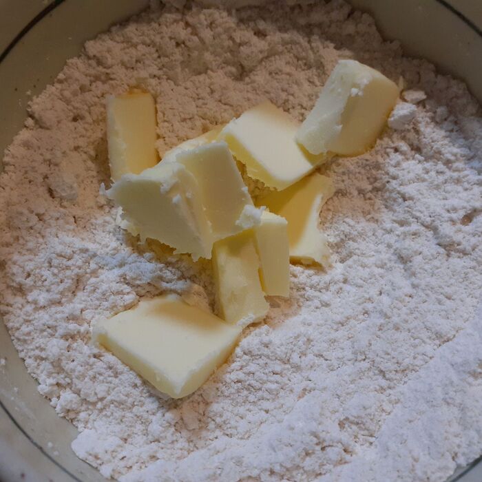 ②小麦粉と砂糖を混ぜ合わせ、冷たいバターを加えて、指先で混ぜ合わせ、そぼろ状態にする。