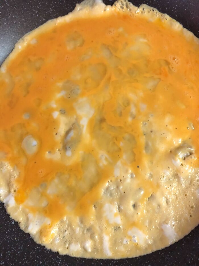 溶き卵をフライパンに入れ、キャベツ、餃子、とろけるチーズを乗せます