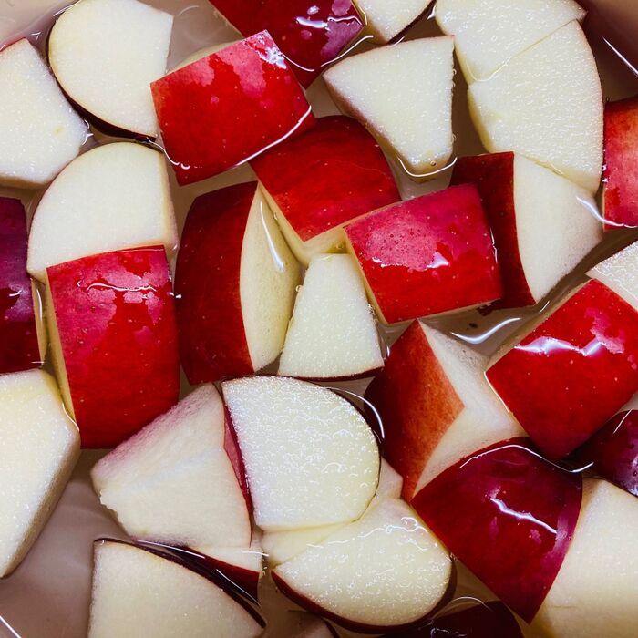 ②りんごはよく洗い8等分のくし切りにしさらに4等分に切り塩水（分量外）につけてザルにあげる。