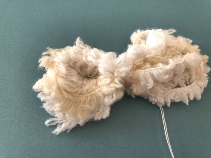 毛糸を型紙に３〜４回巻き付け糸で縛ります
