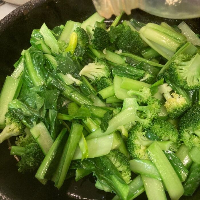 フライパンにごま油を入れて青菜を炒めます