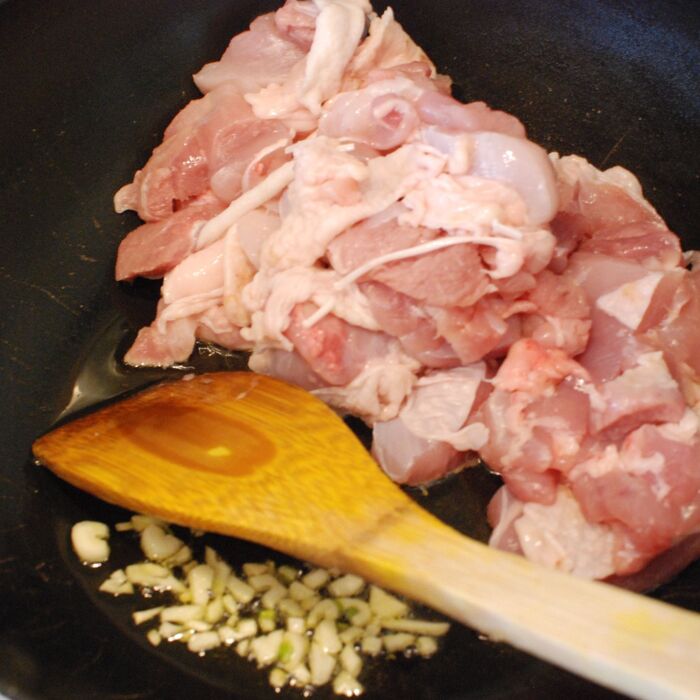 オリーブオイルでにんにくを炒め、鶏もも肉を炒めます