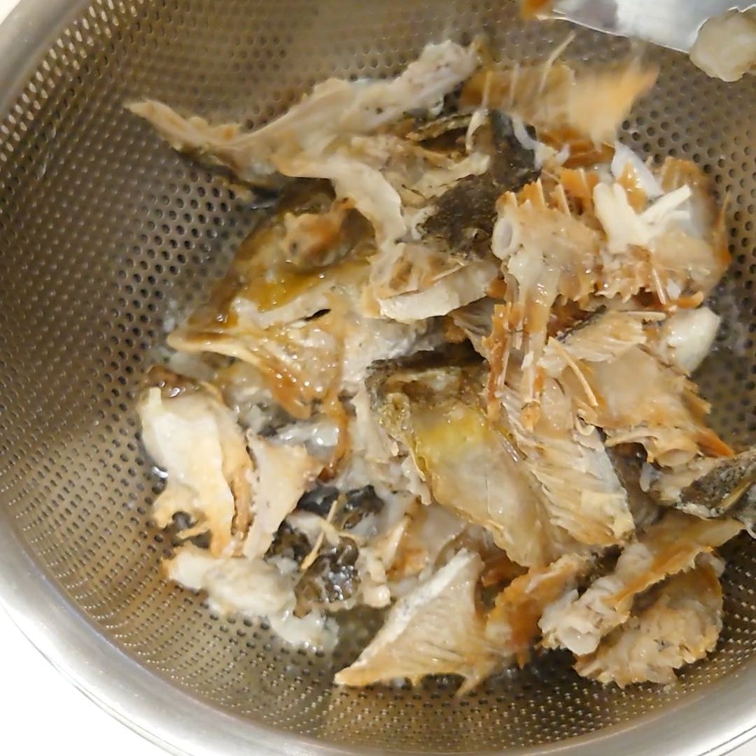 大きな骨をザルでとる。