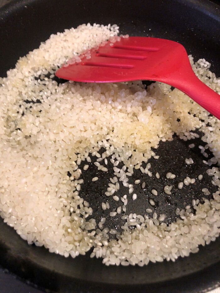 米をオリーブオイルで炒め、白ワインを加えます。