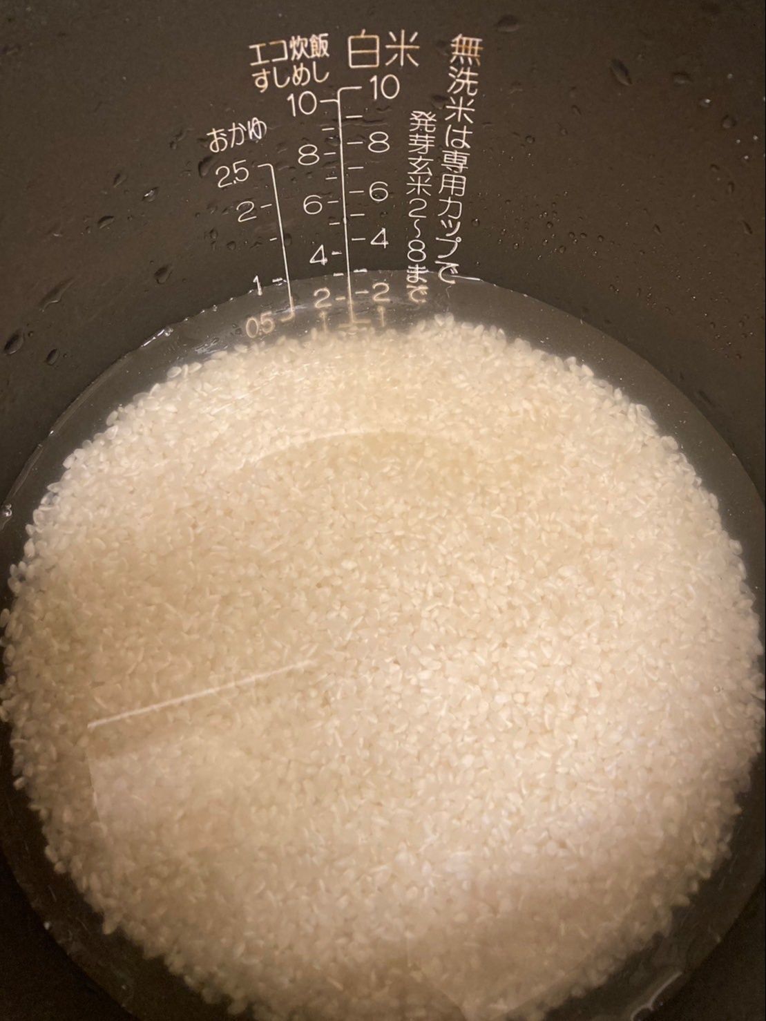 研いだお米をジャーの内釜に入れて、酒と白だしを先に入れてから目印まで水を入れます