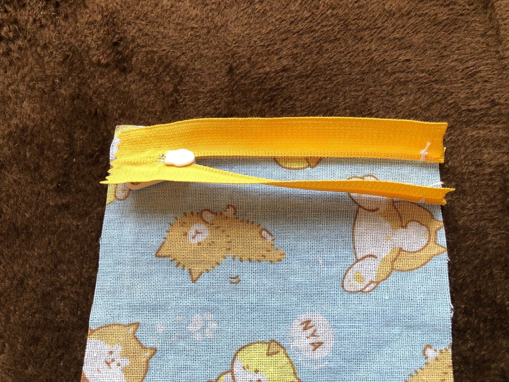 ファスナーの上に布地を重ねて仮縫いし、ファスナーと2枚の布地を重ねます