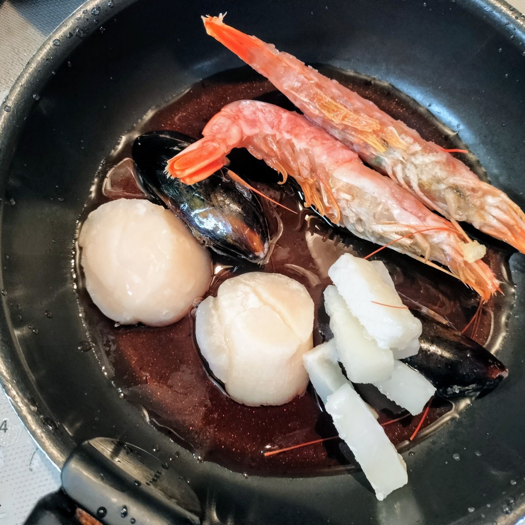2.別のフライパンに、赤ワインと具材（赤海老・ムール貝・イカ・ホタテ）を入れる→蓋をして蒸す