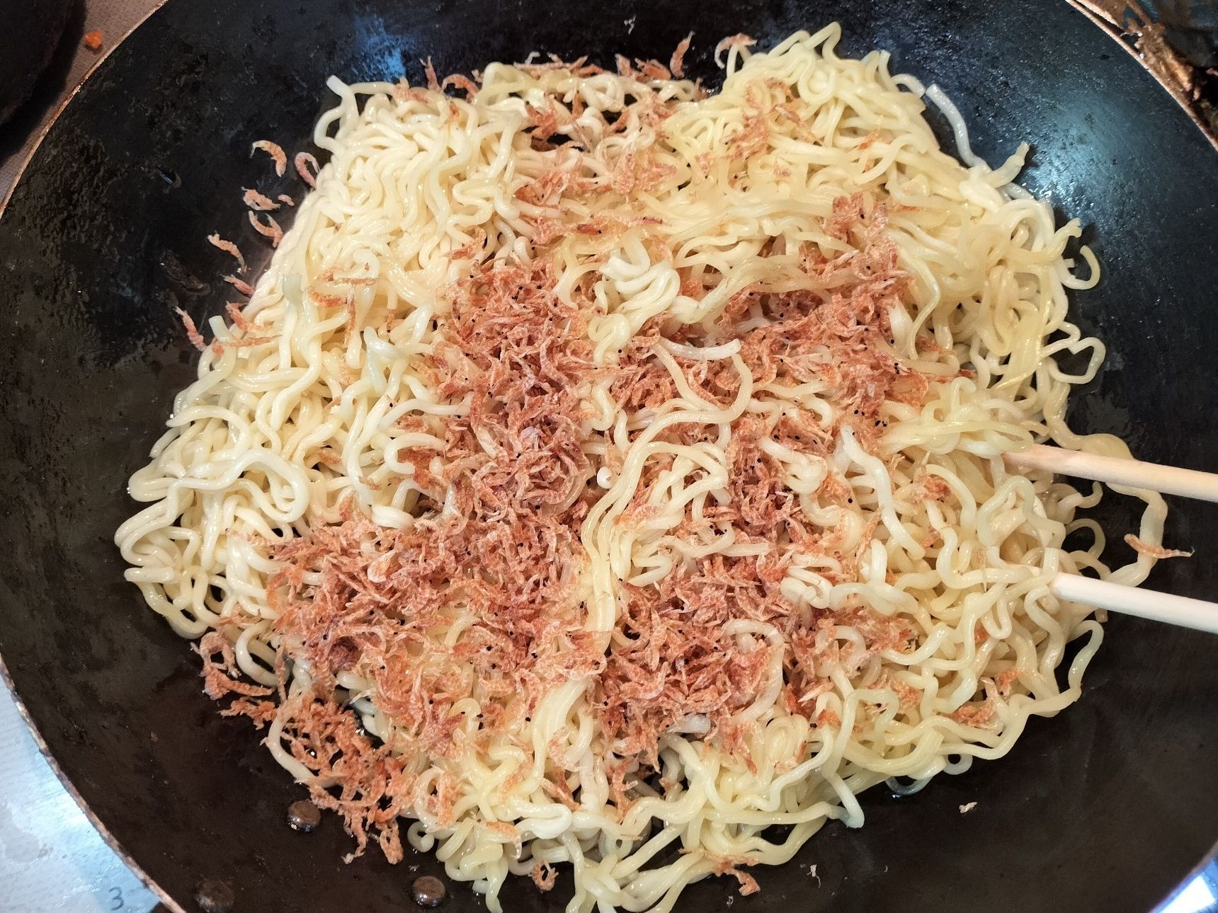 3.鉄フライパンを熱し、ごま油を入れる→温めた麺と素干しアミエビを入れてしっかりと炒める→粉末ソースと海鮮XO醤を加えて炒める