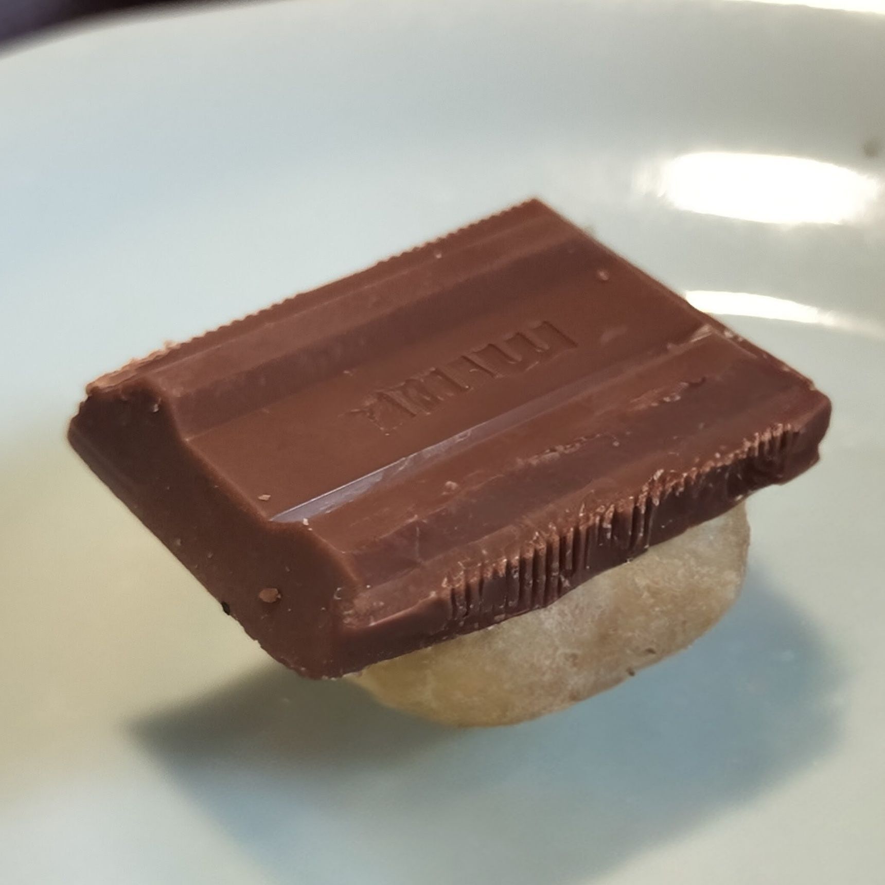 2、耐熱皿に、（欠けなかった）丸い形のマカダミアナッツ一粒に板チョコ1片をのせて、電子レンジで1分ほど加熱する