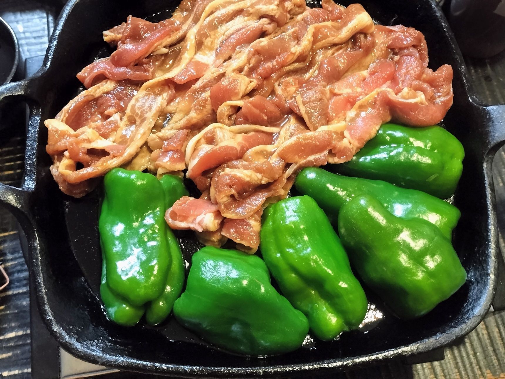 4、熱した鉄フライパンに、ごま油を入れる→手順2の豚バラ肉とピーマンを入れる→卓上ヒーターにのせ、弱（300W）でじっくり焼く