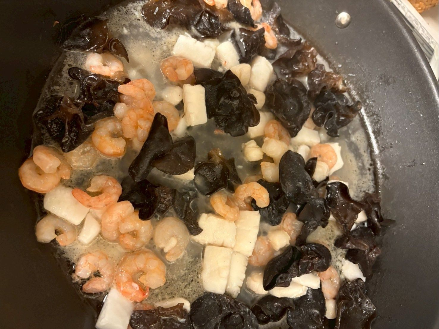 水で戻したキクラゲとシーフードミックスに日本酒をかけて、ごま油で炒めます