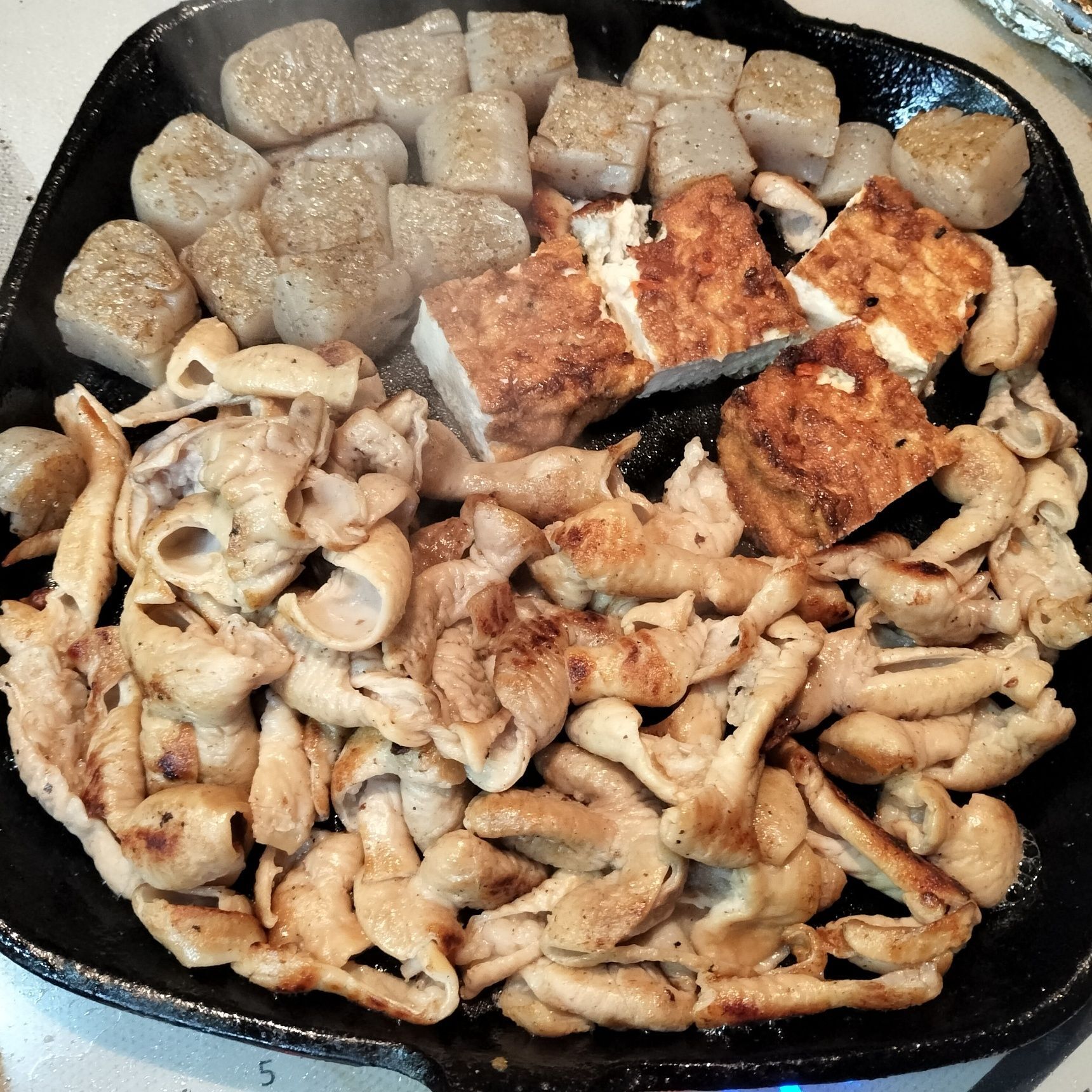 4、鉄フライパンを熱し、ごま油を入れる→豚もつとこんにゃくを入れて、強火で表面をサッと焼く→豚もつに、塩・粗挽きをふりかける→中火で豚もつとこんにゃくにしっかり焼き色がつくまで焼く→食べやすい大きさに切った厚揚げを加えて、両面を焼く