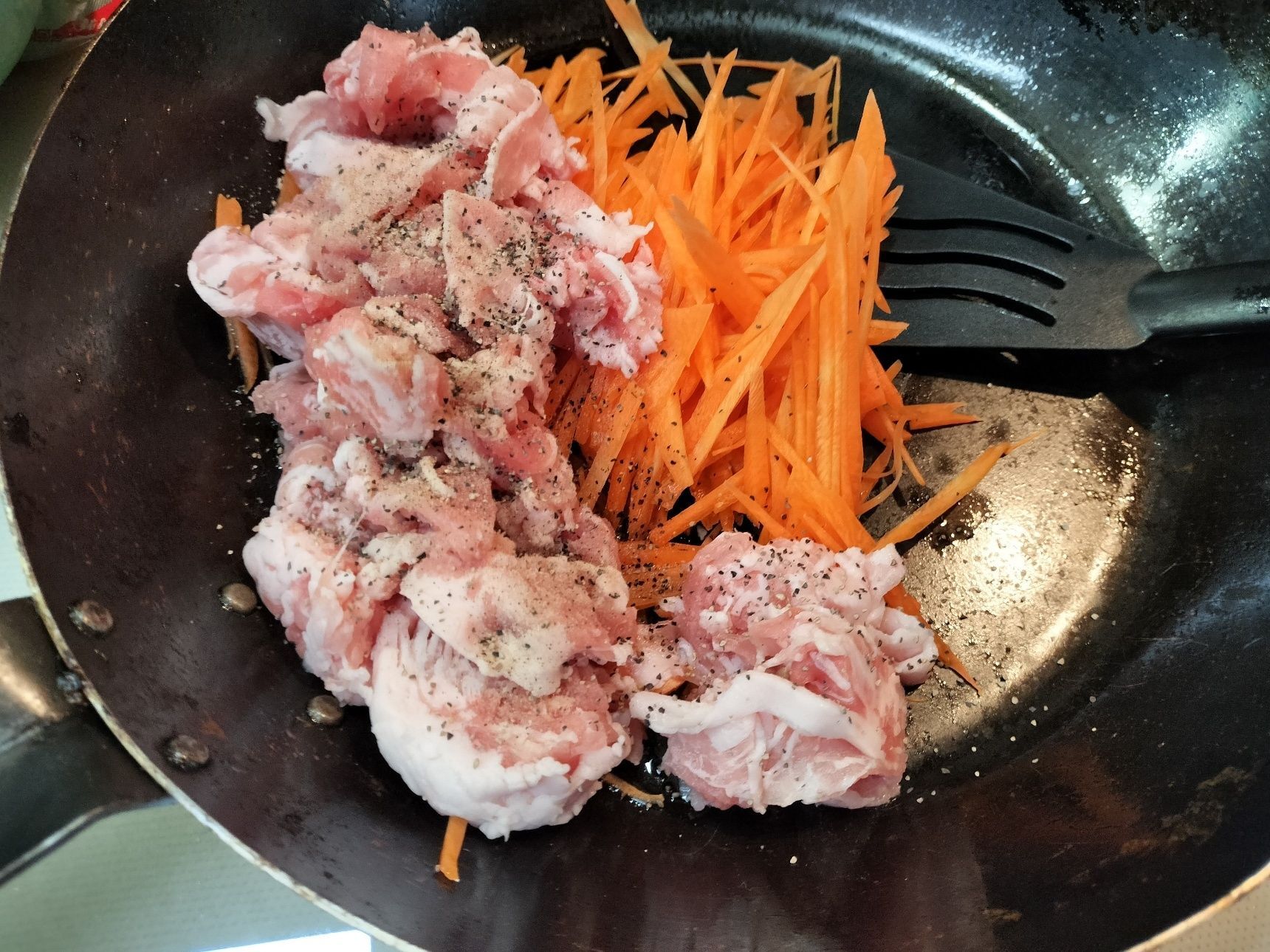 2.別の熱した鉄フライパンにごま油を入れる→豚バラ肉・人参・塩・粗挽き胡椒を入れて炒める→ターツァイを加えて、サッと炒める