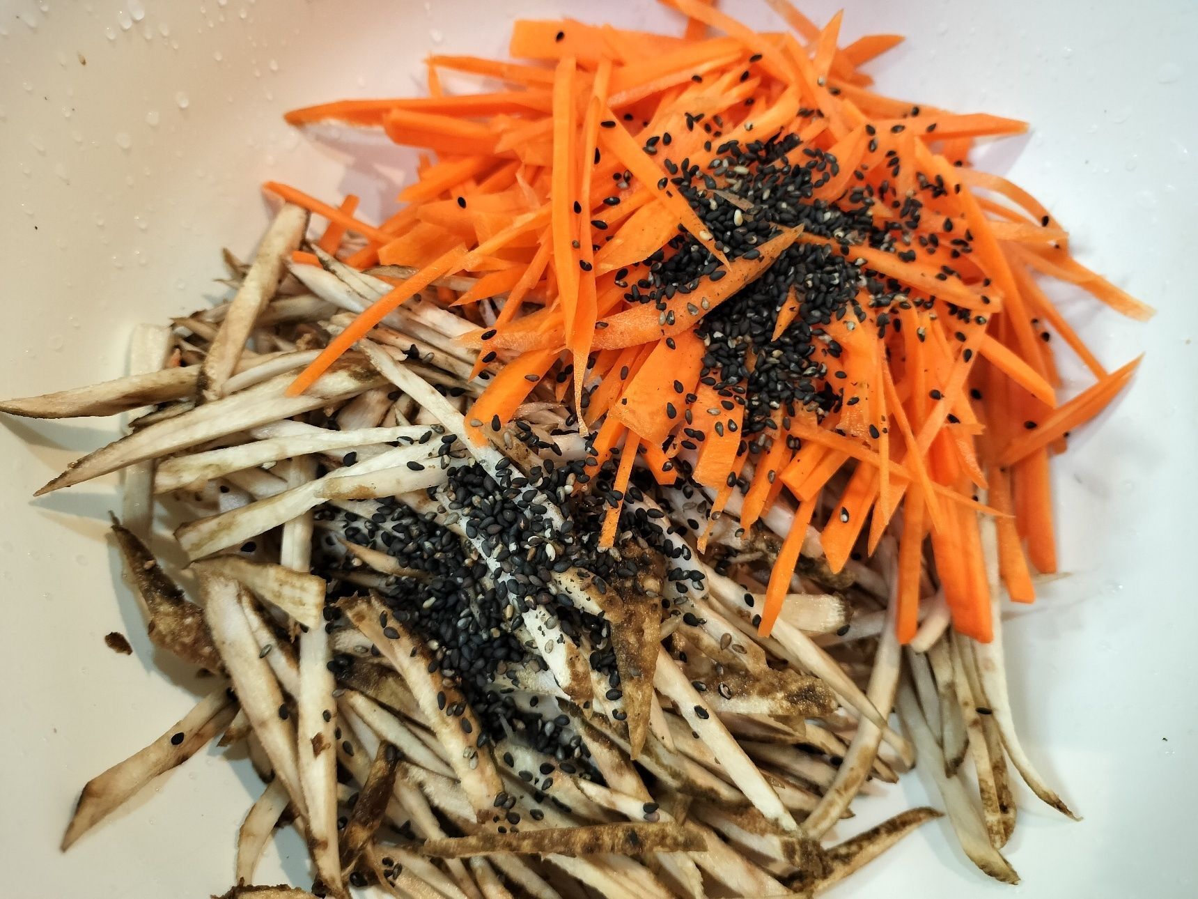 3、ボウルに、ごぼう・人参を入れる→炒りごま（黒）を加えて混ぜる→全体に小麦粉をまぶす→水を加えて衣をつける