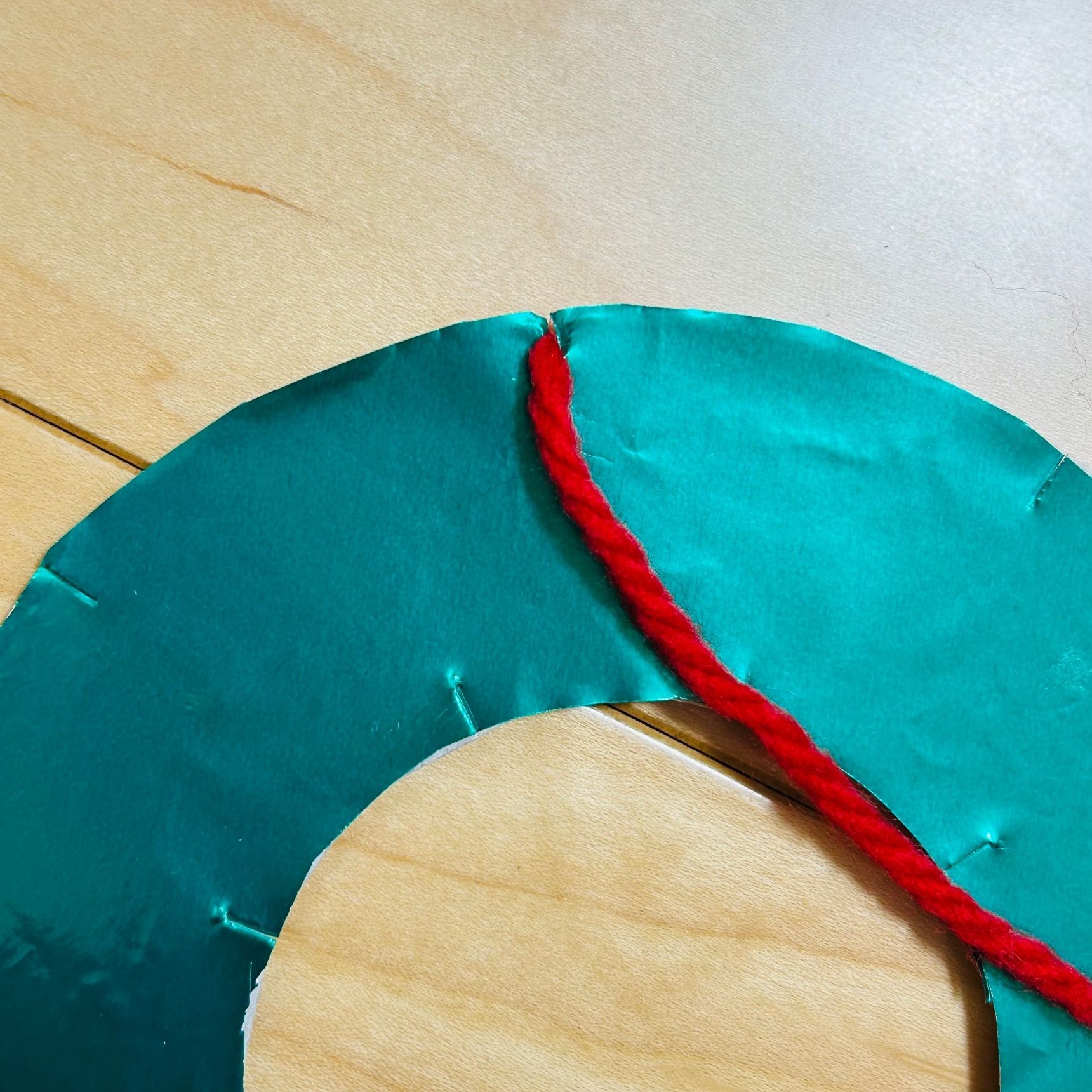 ⑤毛糸を④の切り込みに引っ掛けながらリースを巻いていきます