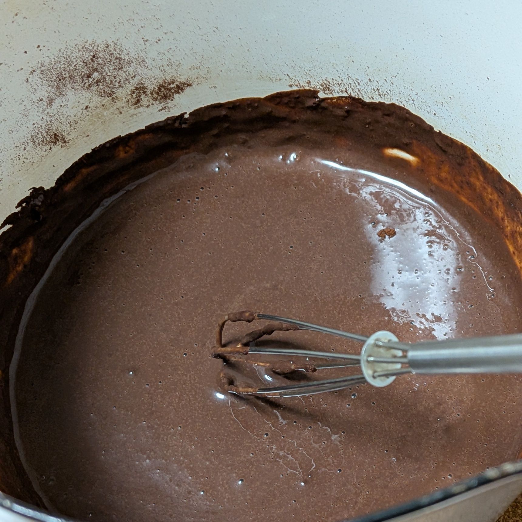 2.牛乳を少しずつ入れ、その都度よく混ぜる。ココアにダマが残らないように