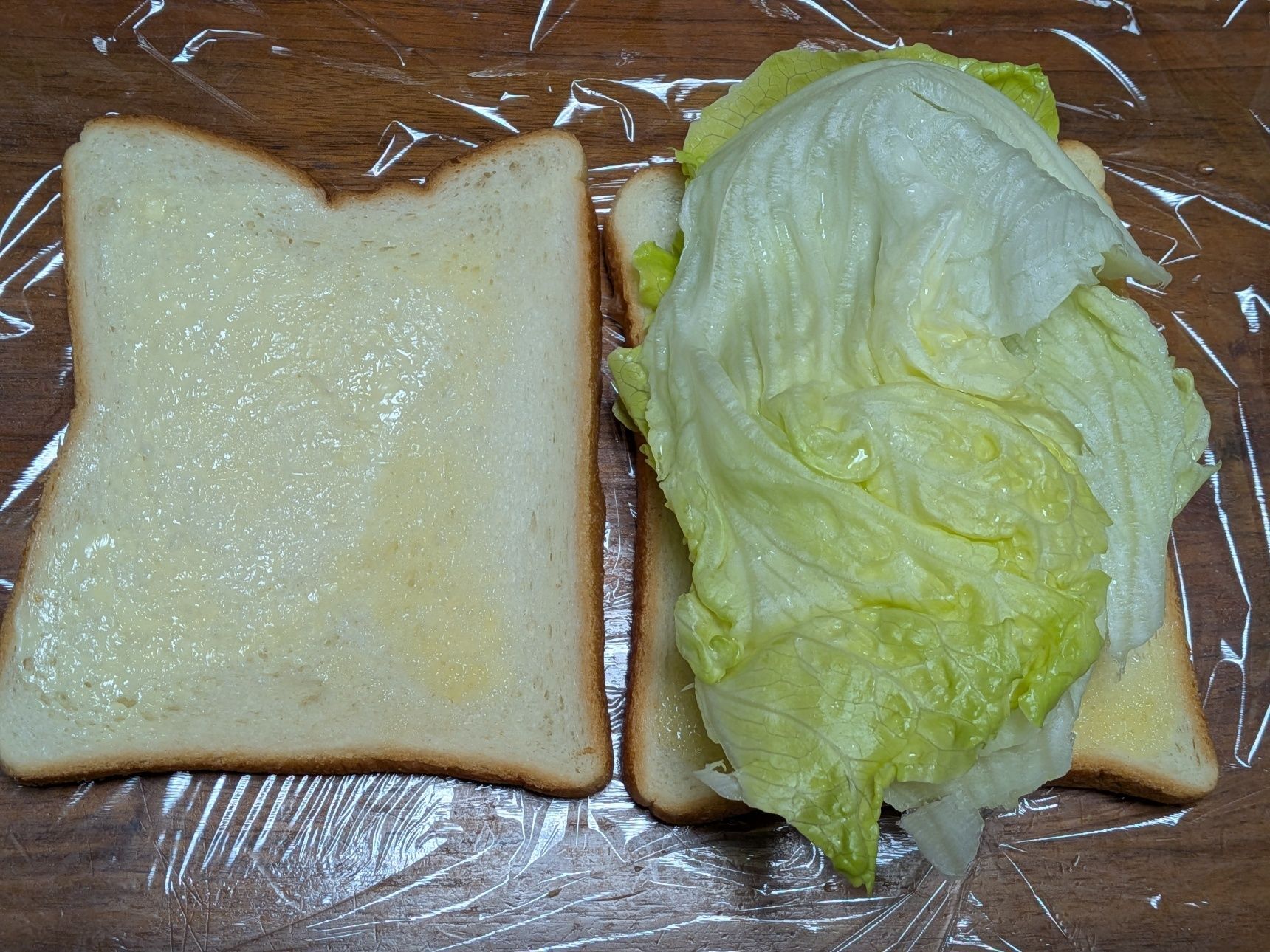 5. お皿の上にラップをしき、食パンにバター10gを塗る。（2枚分）レタスをのせる。