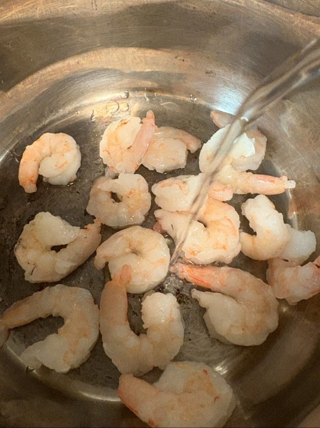 冷凍エビは水で周りの氷を流してから鍋に入れ日本酒をかけて酒蒸しにします。