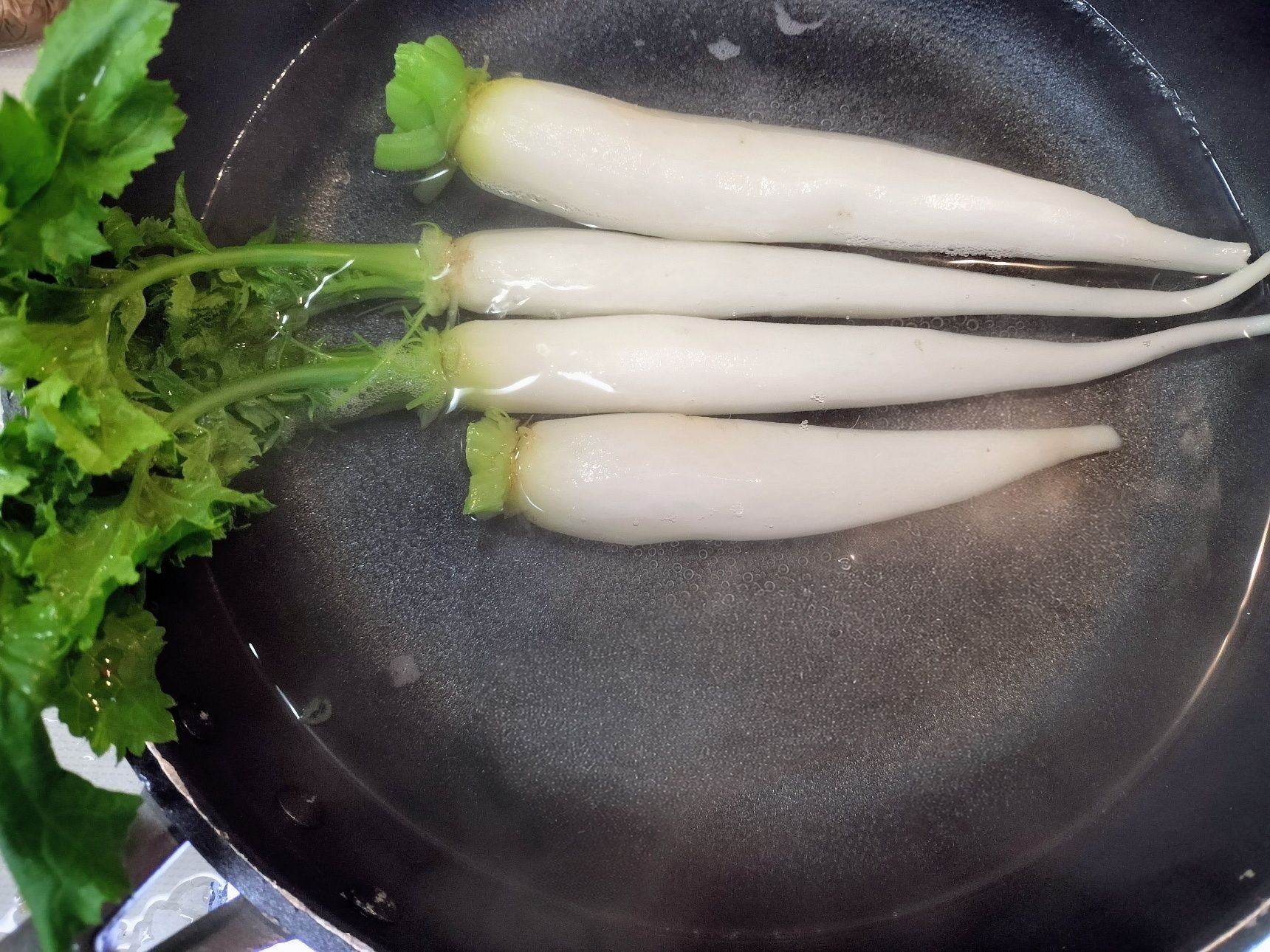 3、根の部分（4本）は皮を剥き、柔らかくなるまで茹でる→ザルにあけ、粗熱を取る→葉なし大根の半分から下は厚めの輪切りにして、半分より上は縦四つ切りにする