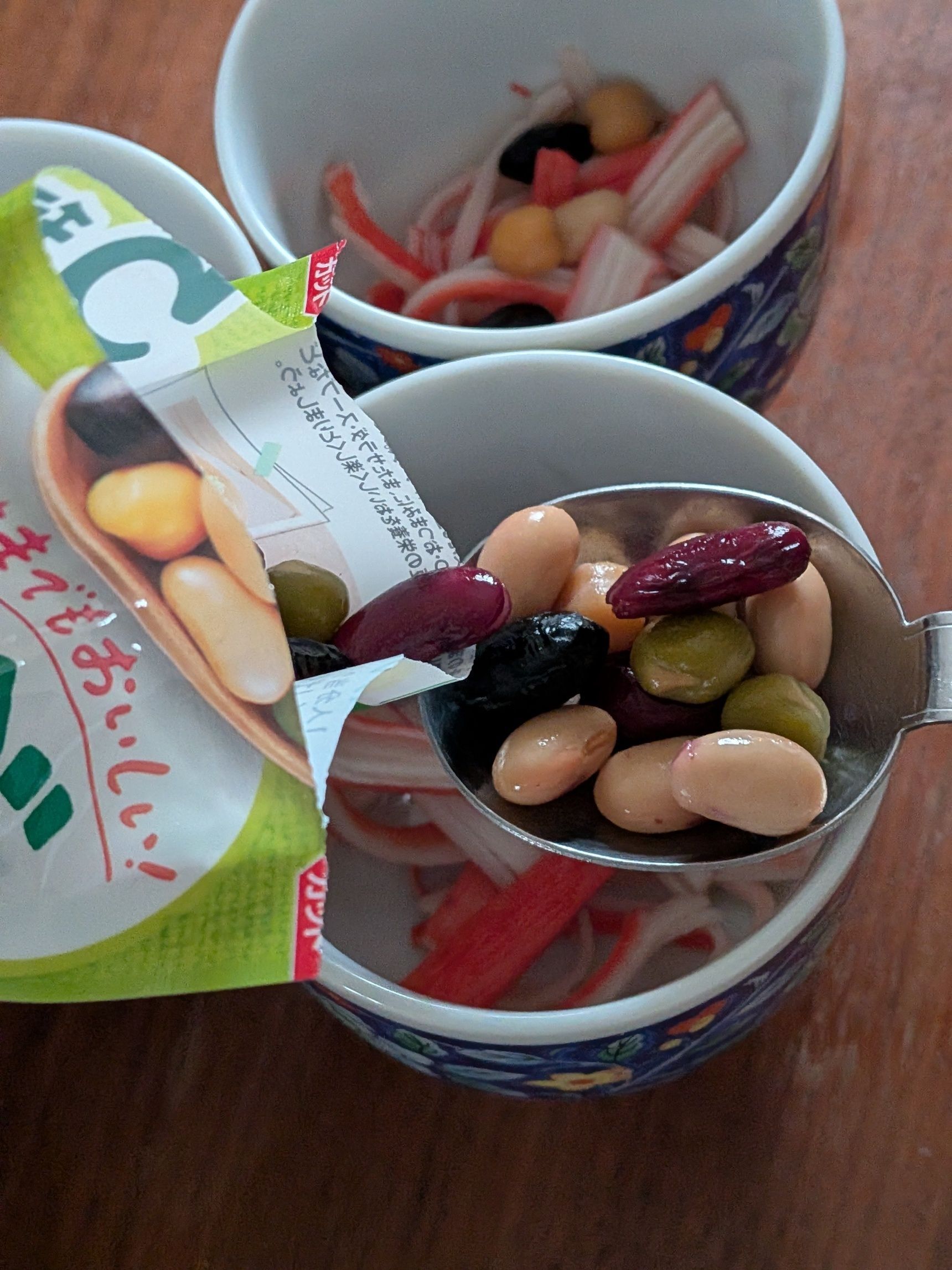 2. カニカマをさいて茶碗蒸し用の器にいれる。蒸し豆も大さじ1ずつ入れる。