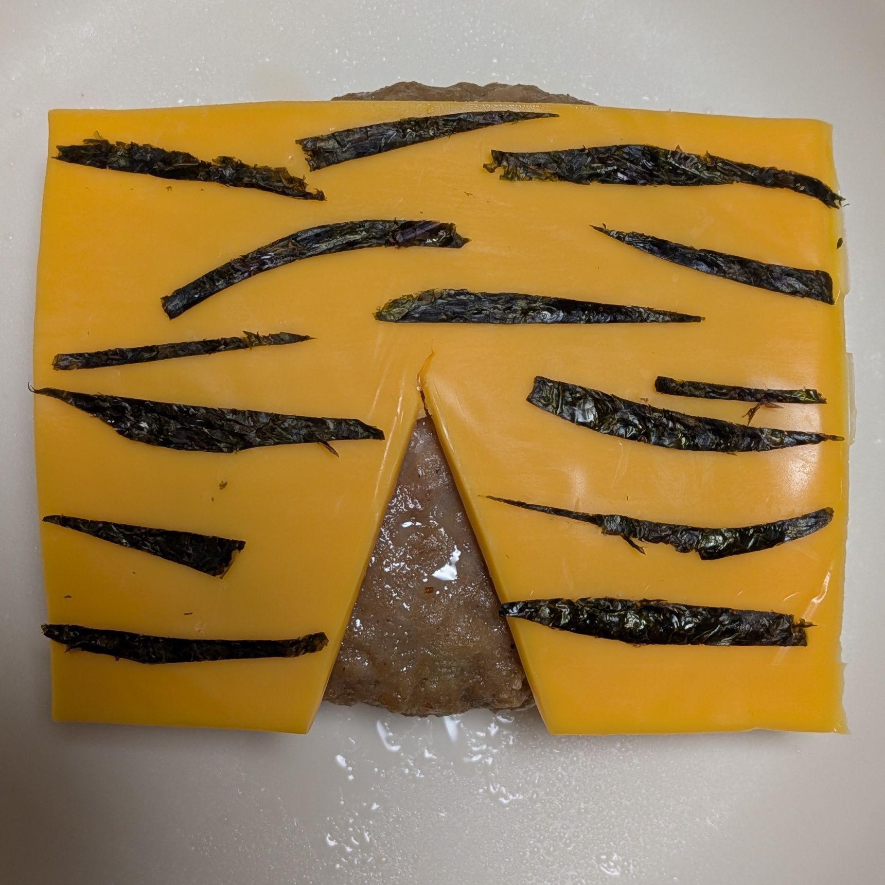 2.チェダーチーズを鬼のパンツの形に切る。細かく切った海苔をのせる。解凍したハンバーグにのせる